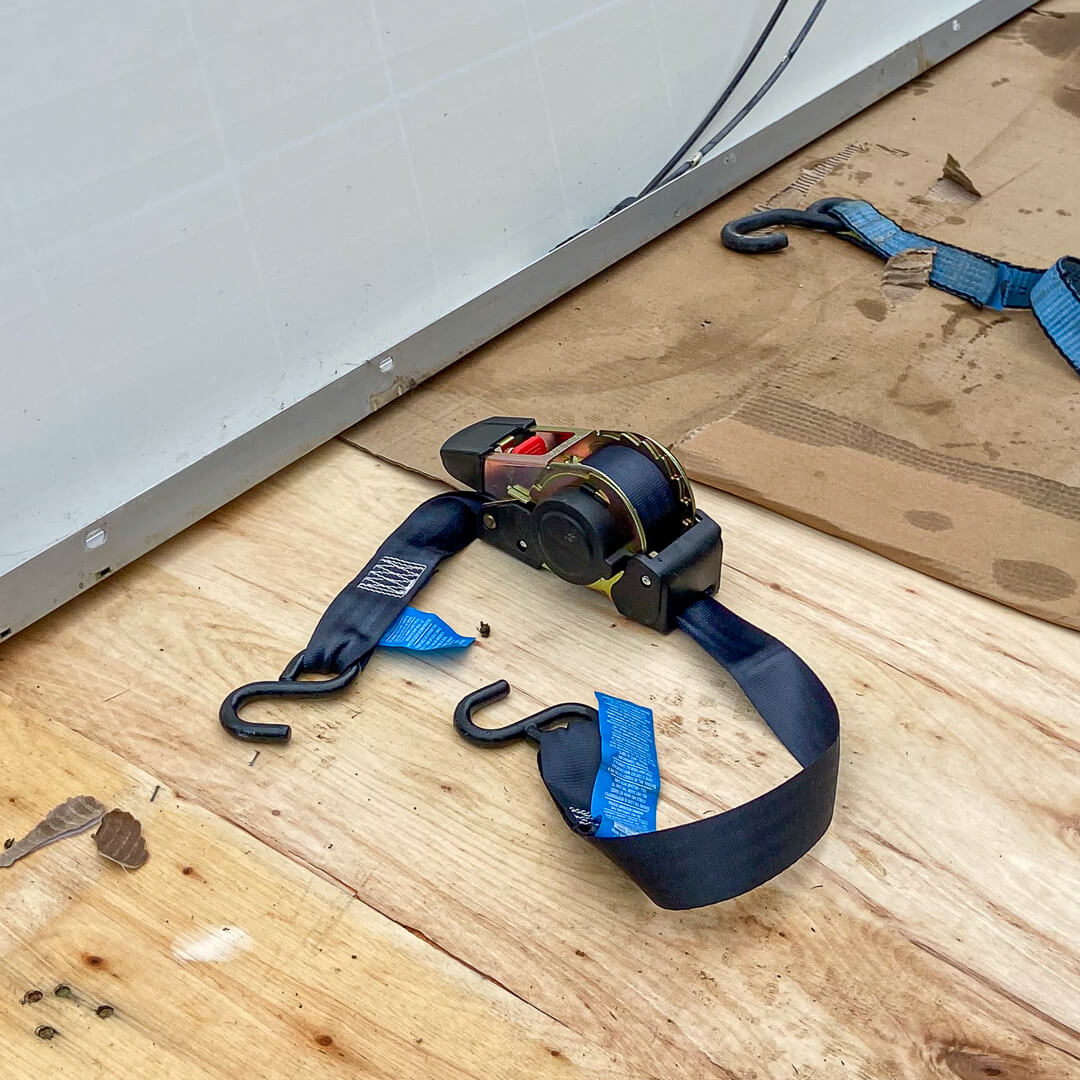 Ratchet strap on a wooden floor with tools in the background